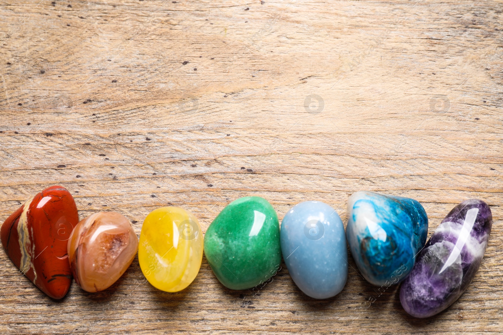 Photo of Flat lay composition with different gemstones on wooden table, space for text