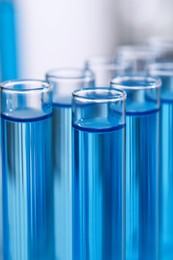 Photo of Test tubes with reagents on blurred background, closeup. Laboratory analysis