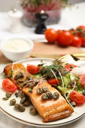 Photo of Delicious salmon with salad and capers on table, closeup