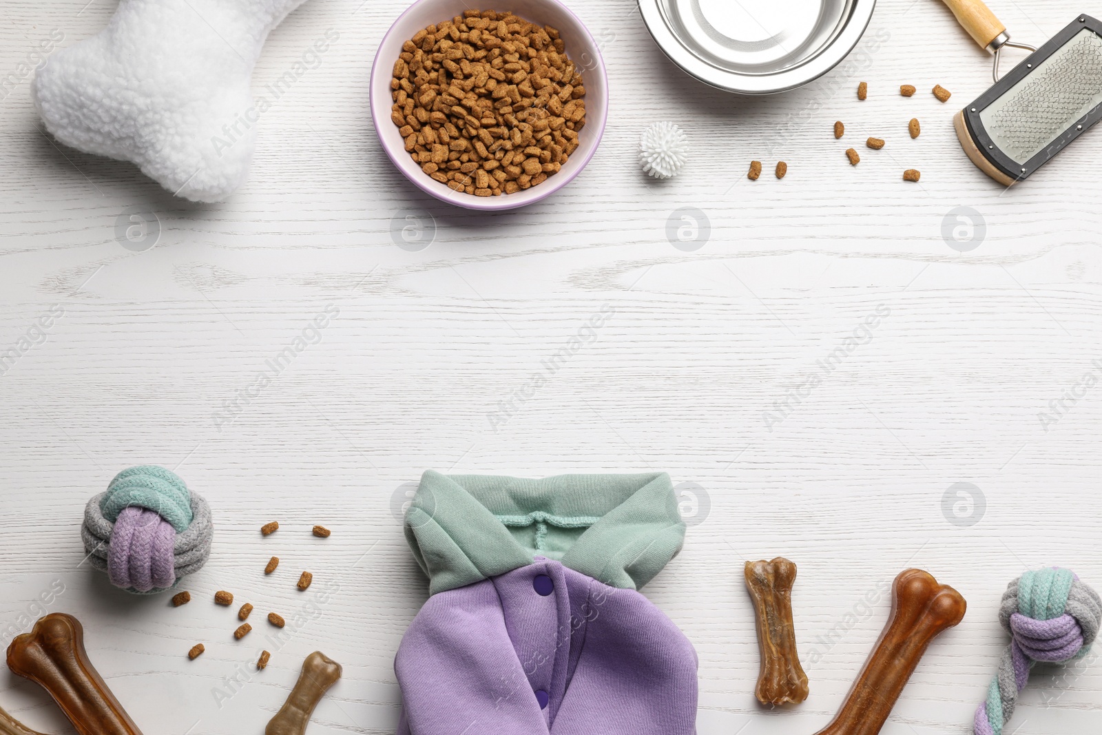 Photo of Flat lay composition with dog clothes, food and accessories on white wooden table. Space for text