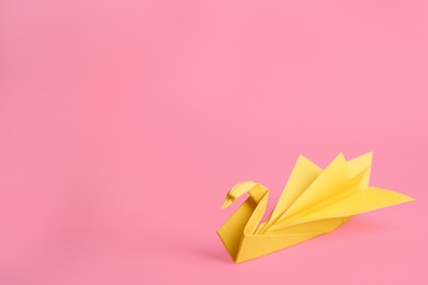 Photo of Origami art. Beautiful paper swan on pink background, space for text