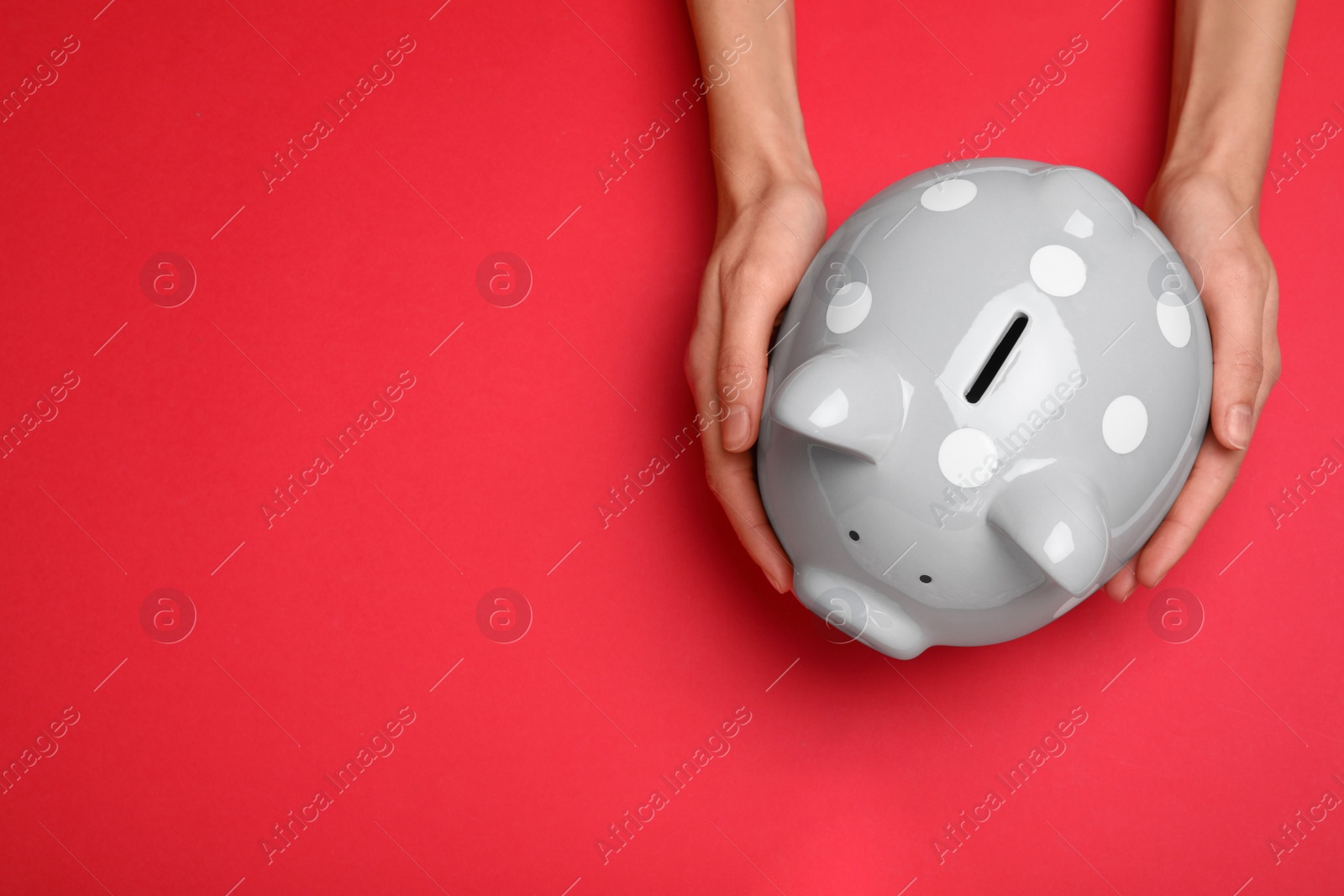 Photo of Woman holding piggy bank on red background, top view with space for text. Money savings