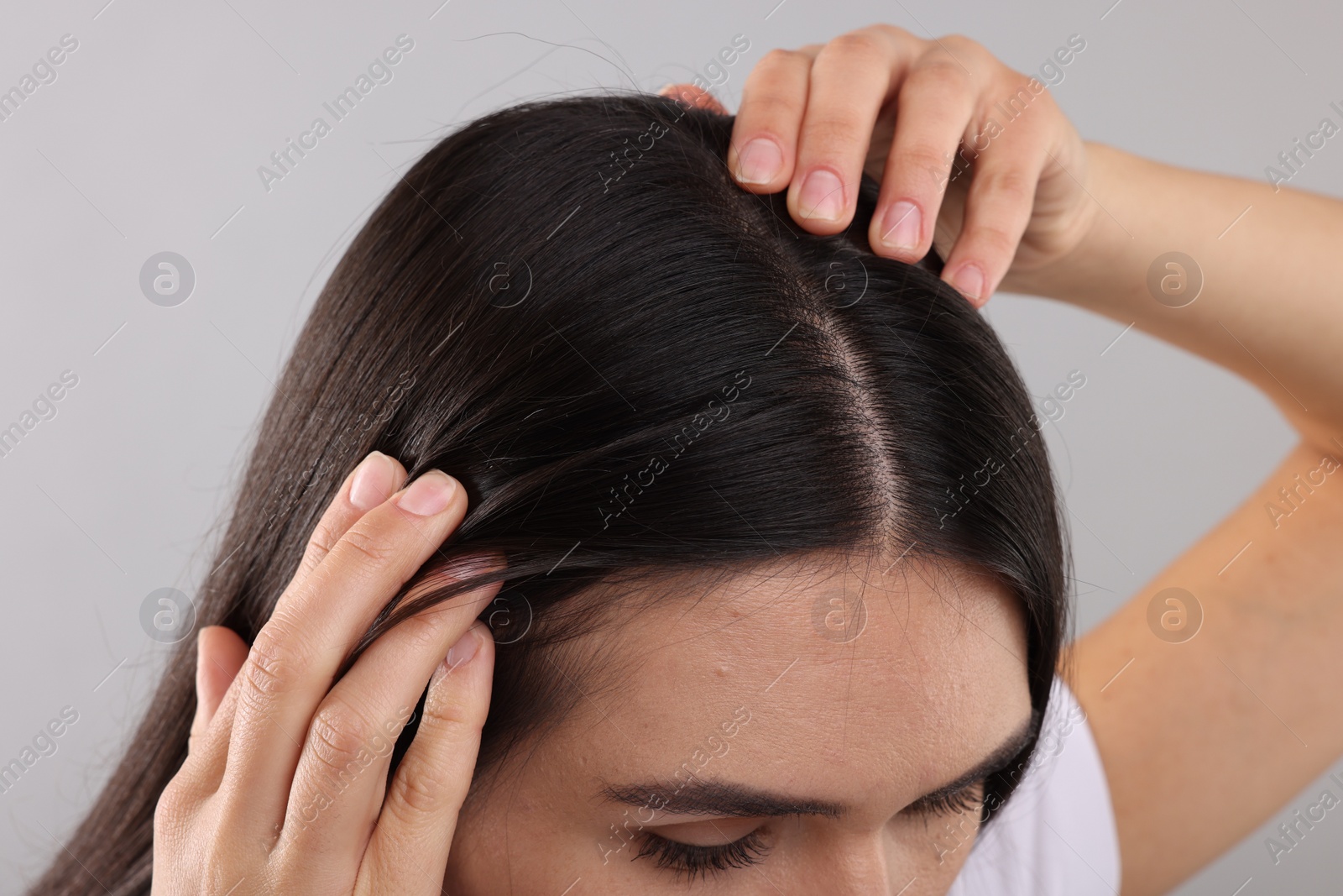 Photo of Woman examining her hair and scalp on grey background, closeup