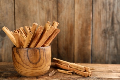 Aromatic cinnamon sticks on wooden table, space for text