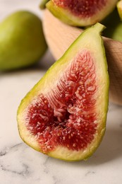 Photo of Half of green fig on white marble table, closeup