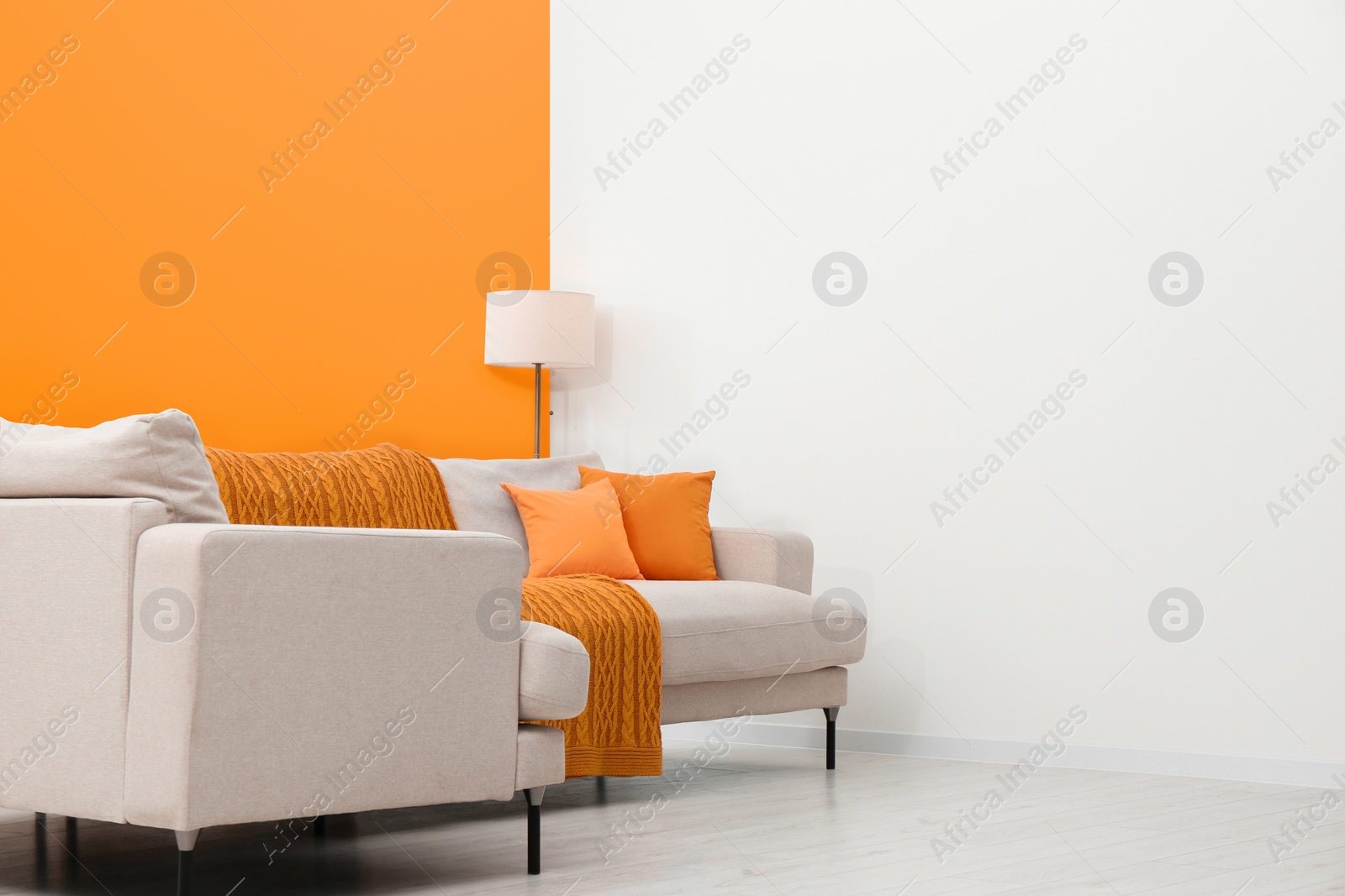 Photo of Stylish room with cosy sofa near orange wall. Interior design