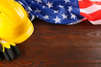 Photo of Yellow hard hat, gloves and American flag on wooden table, space for text