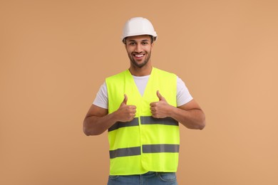 Photo of Engineer in hard hat showing thumbs up on beige background