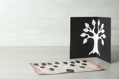 Card and paper with family tree templates on light wooden table. Space for text