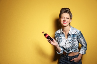 MYKOLAIV, UKRAINE - NOVEMBER 28, 2018: Young woman with bottle of Coca-Cola on color background, space for text