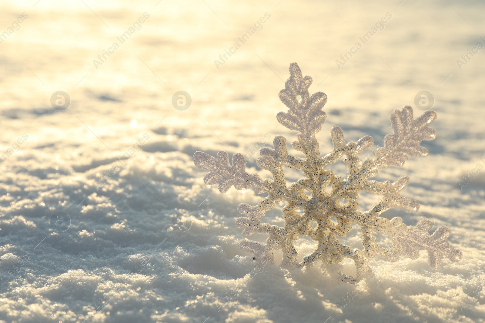 Photo of Beautiful decorative snowflake in white snow, outdoors. Space for text