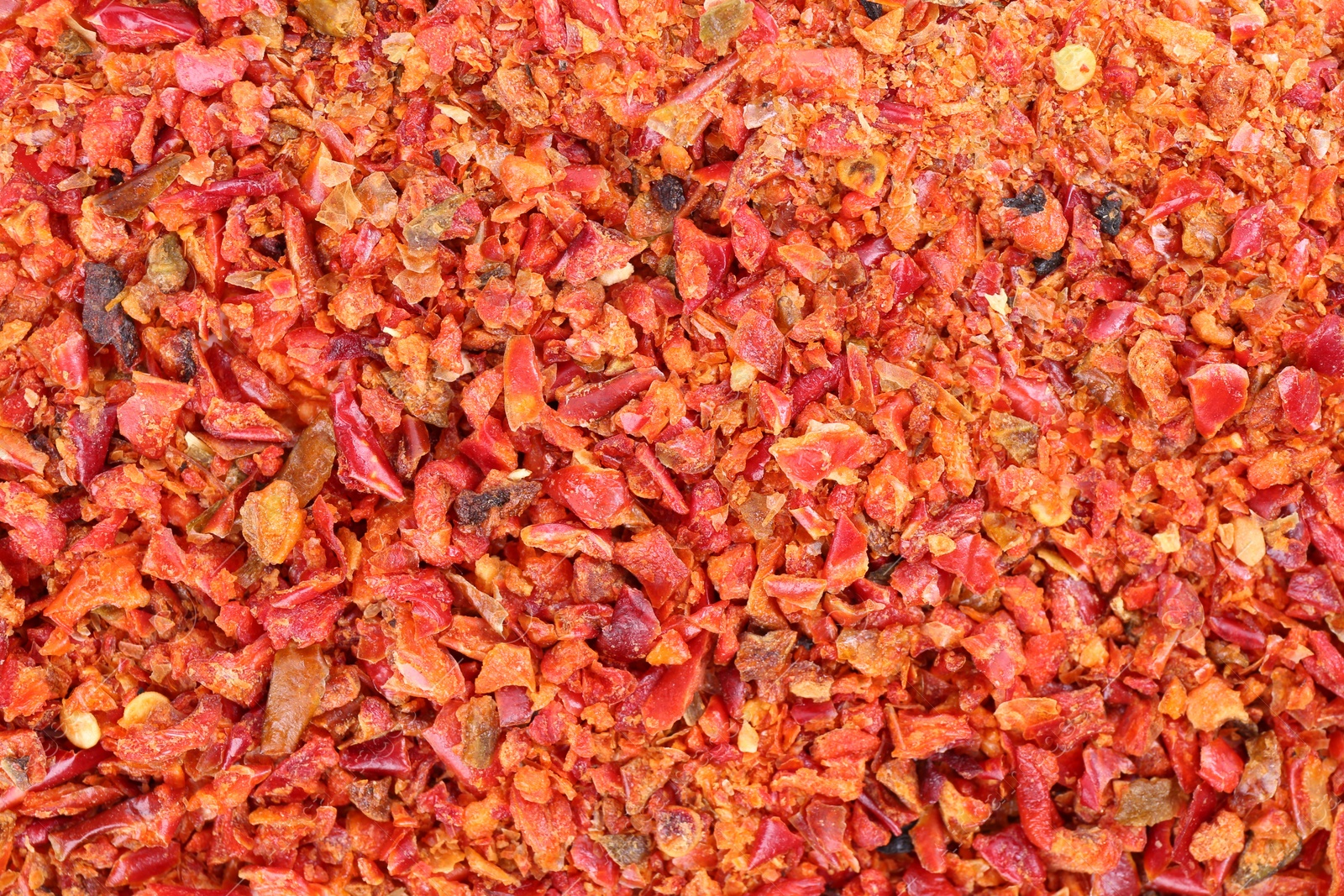 Photo of Aromatic spice. Red chili pepper flakes as background, top view