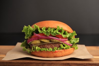 Photo of One tasty burger on wooden table, closeup