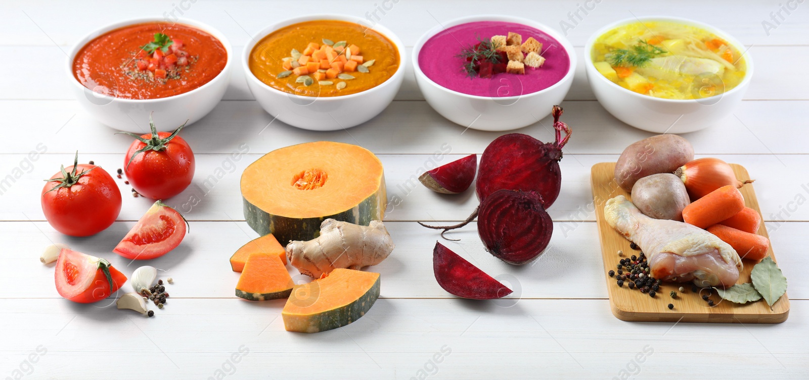Photo of Tasty broth, different cream soups in bowls and ingredients on white wooden table