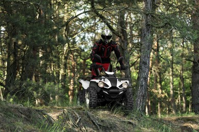 Photo of Man driving modern quad bike in forest. Extreme sport