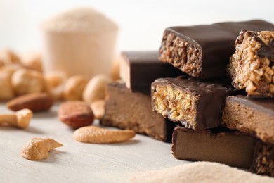 Photo of Different tasty protein bars and nuts on white table, closeup. Space for text