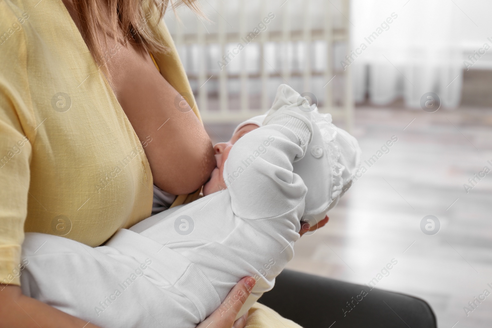 Photo of Young woman breast feeding her little baby at home, closeup