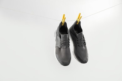 Photo of Stylish sneakers drying on washing line against light grey background, space for text