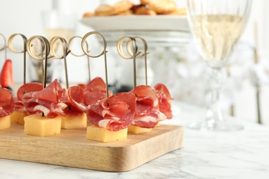 Tasty canapes with cheese and ham on white marble table, closeup. Space for text