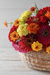 Photo of Beautiful wild flowers in wicker basket on light wooden table