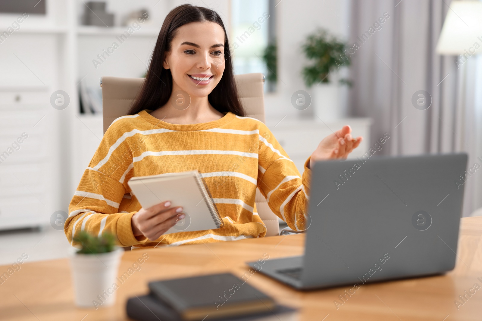 Photo of Young woman using video chat during webinar at table in room