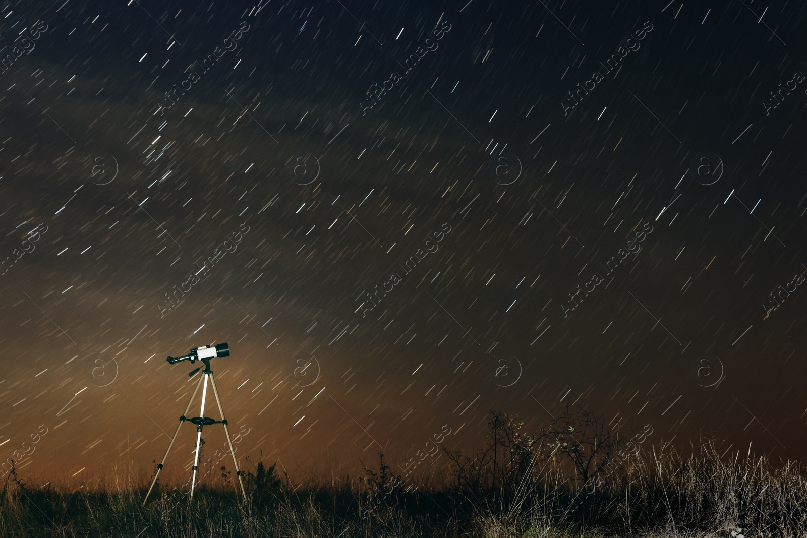 Photo of Modern telescope and beautiful sky in night outdoors. Star trail