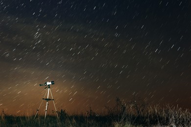 Modern telescope and beautiful sky in night outdoors. Star trail