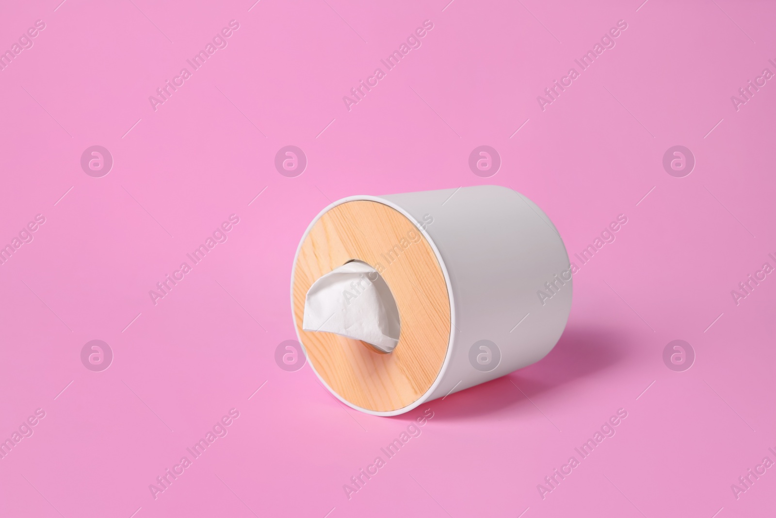 Photo of Holder with paper tissues on pink background