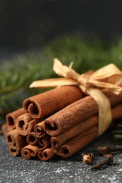 Photo of Different spices. Aromatic cinnamon sticks and clove seeds on dark gray textured table, closeup