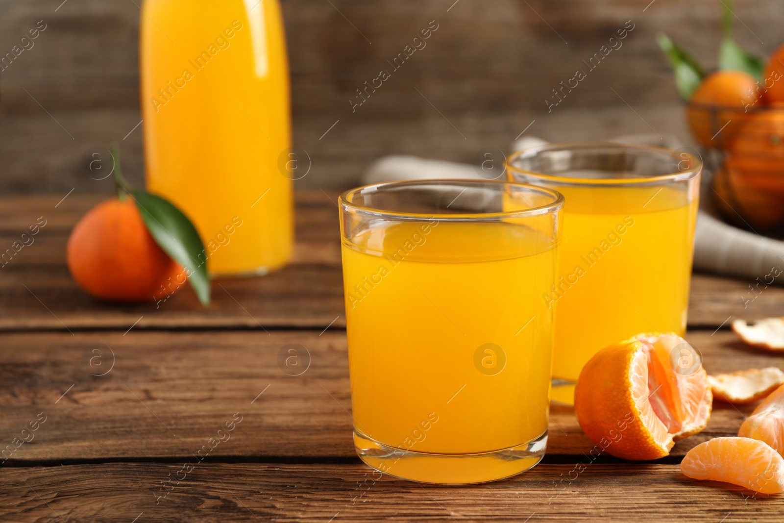 Photo of Glasses of fresh tangerine juice and fruits on wooden table