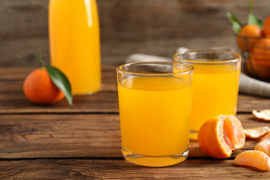 Photo of Glasses of fresh tangerine juice and fruits on wooden table