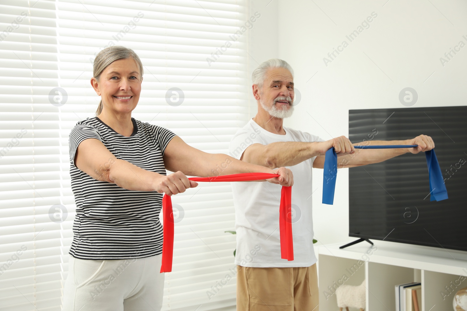 Photo of Senior couple doing exercise with fitness elastic bands at home