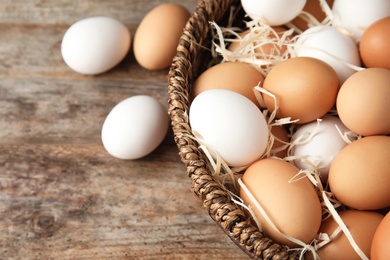 Photo of Basket with raw chicken eggs on wooden background