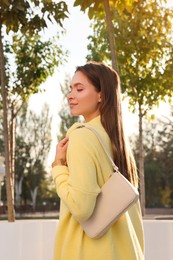 Photo of Fashionable young woman with stylish bag on city street