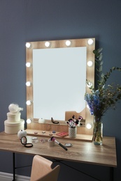 Photo of Table with beautiful mirror and cosmetics in modern makeup room