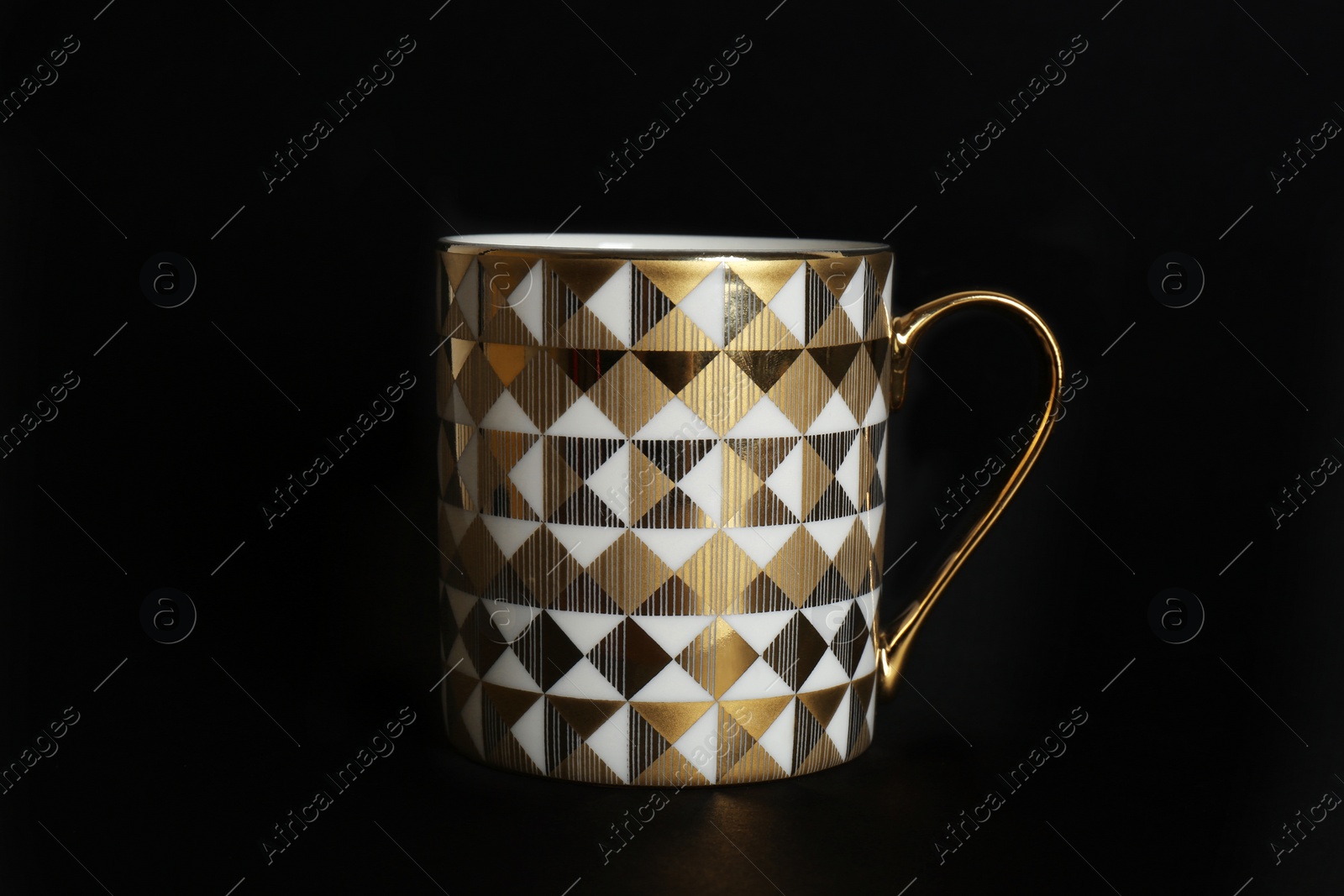 Photo of Cup with gold pattern on black background