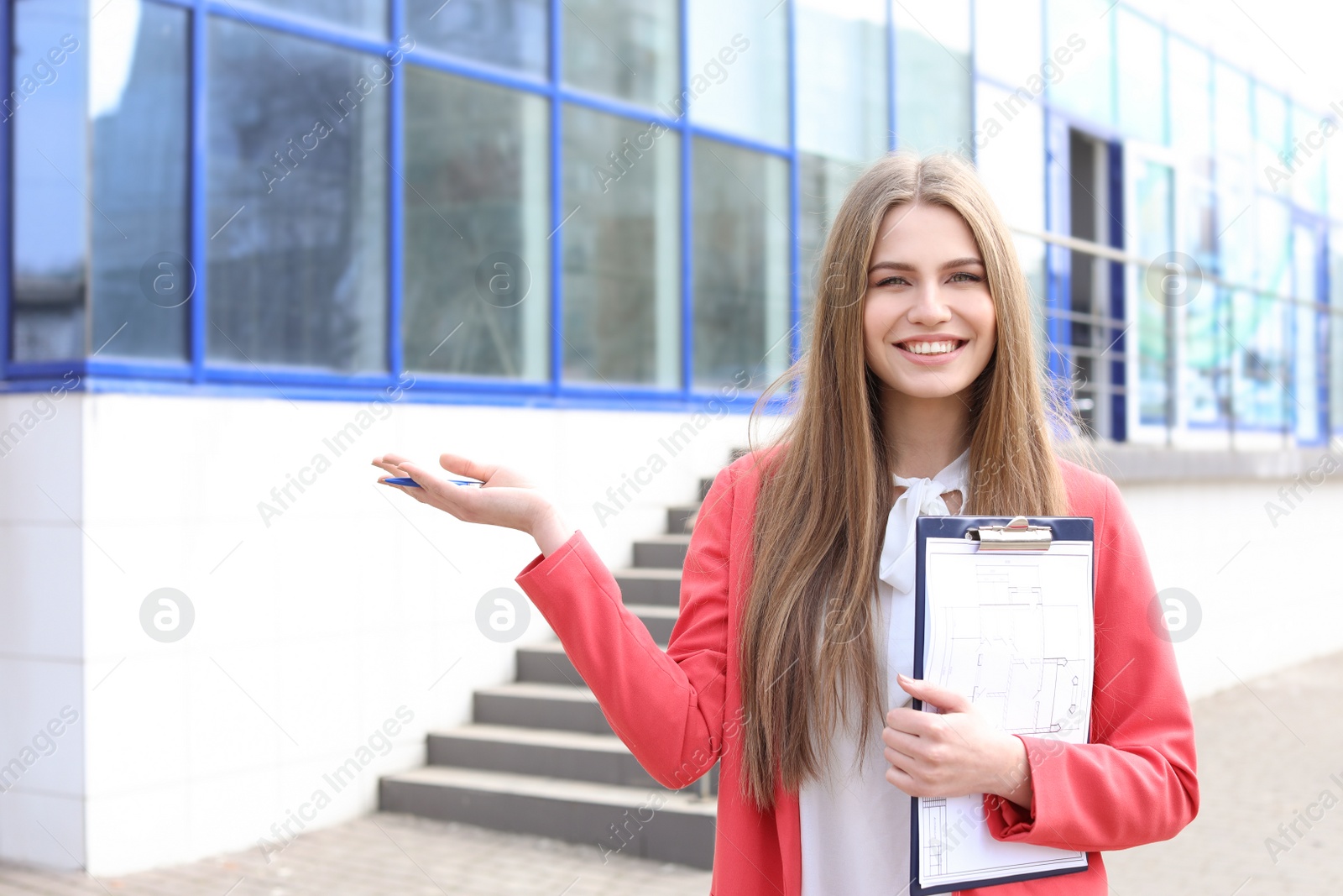 Photo of Beautiful real estate agent with clipboard outdoors