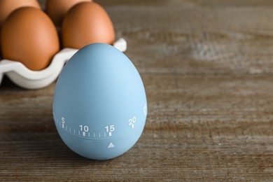 Photo of Kitchen timer and eggs on wooden table. Space for text
