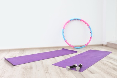 Photo of Hula hoop, yoga mats and dumbbells in physiotherapy gym