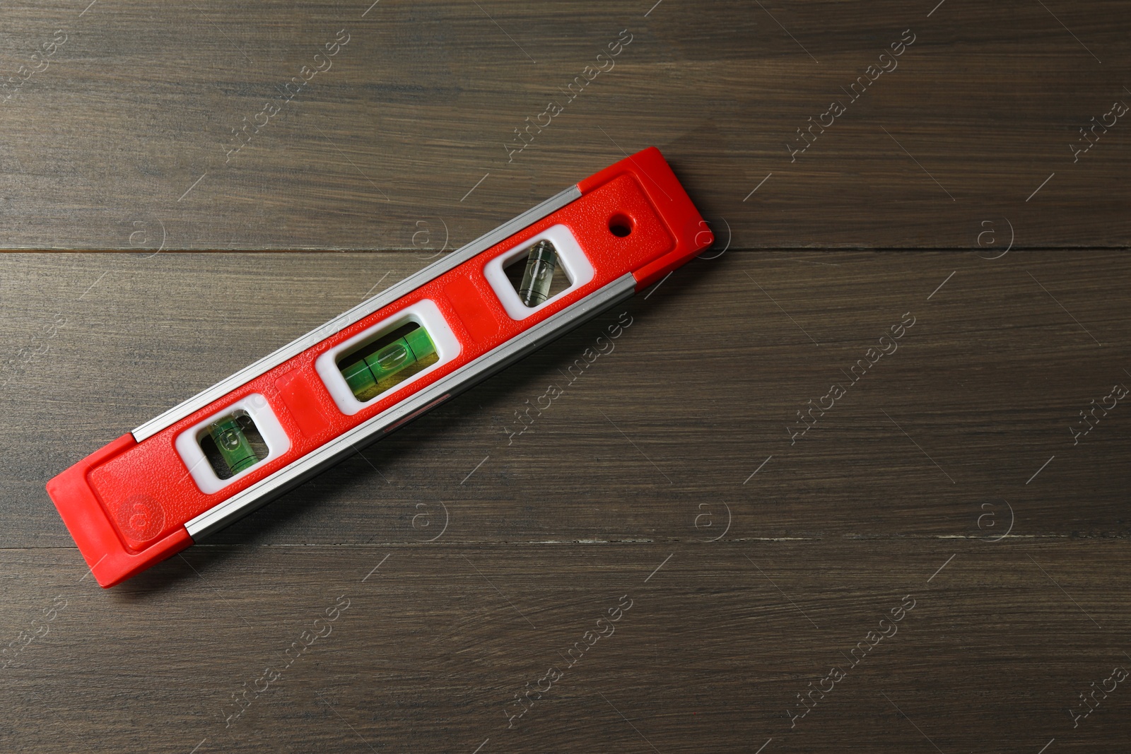 Photo of Red building level on wooden table, top view. Space for text