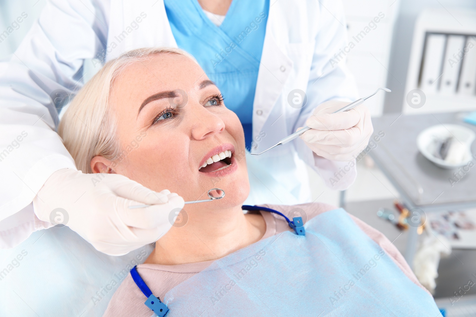 Photo of Dentist examining patient's teeth in modern clinic