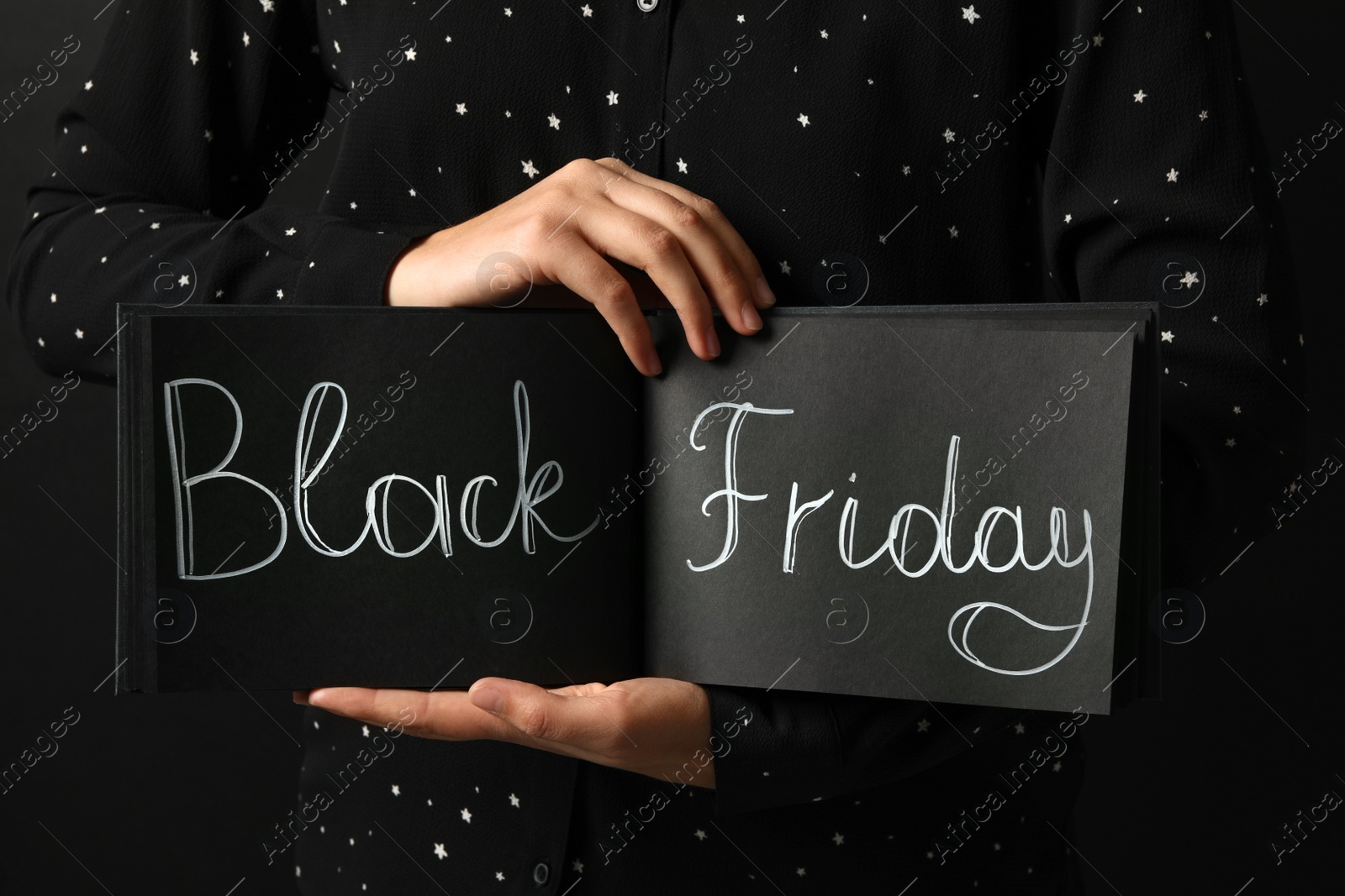 Photo of Woman holding notebook with words Black Friday on dark background, closeup