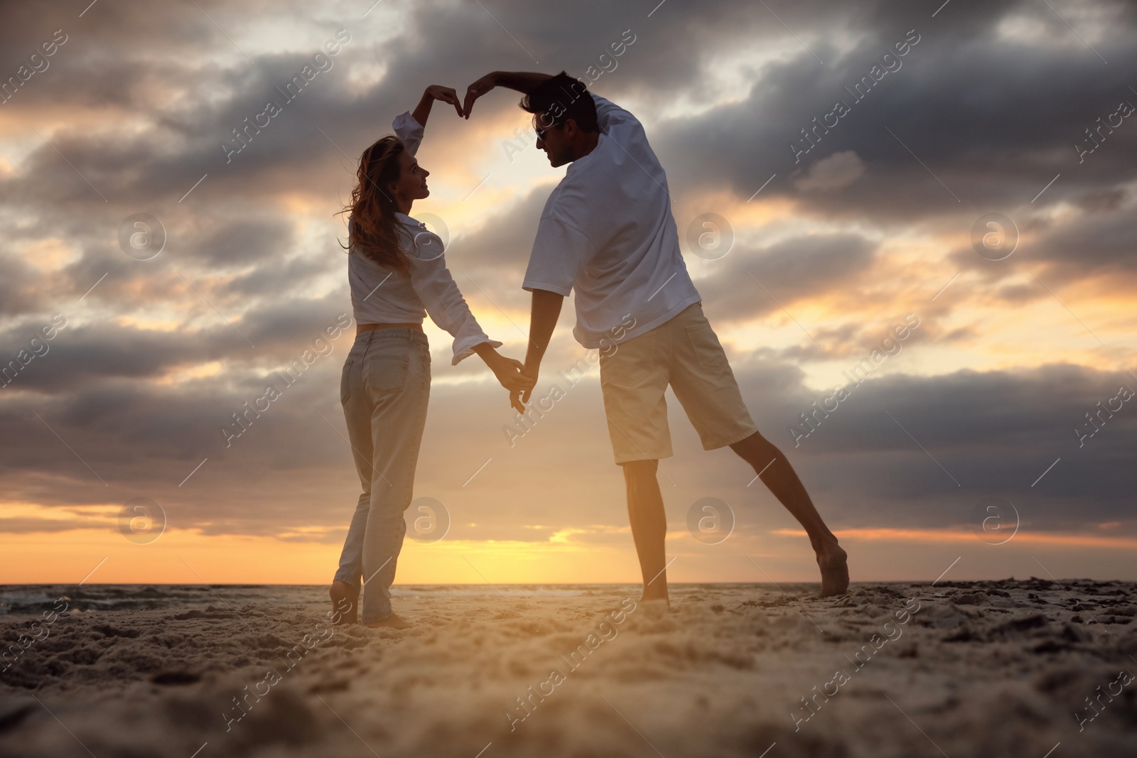 Photo of Happy couple dancing on beach at sunset