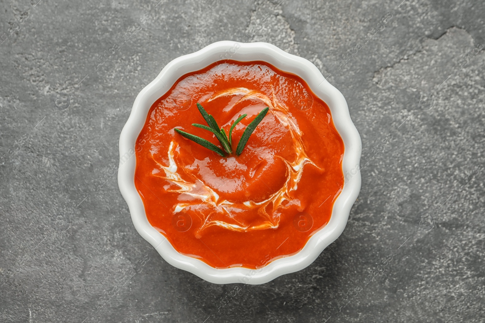 Photo of Bowl with fresh homemade tomato soup on grey background, top view