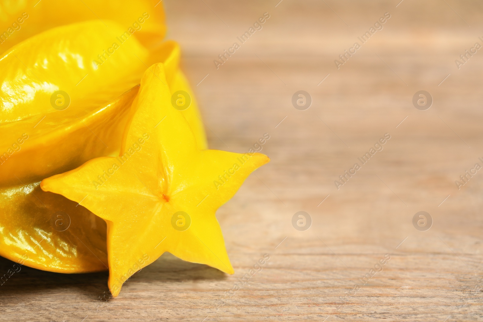 Photo of Delicious carambola and slice on wooden table, closeup. Space for text