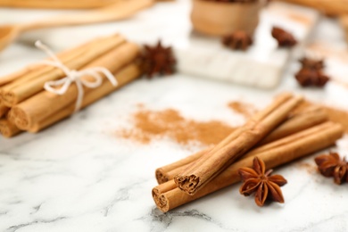 Aromatic cinnamon and anise on white marble table, closeup. Space for text