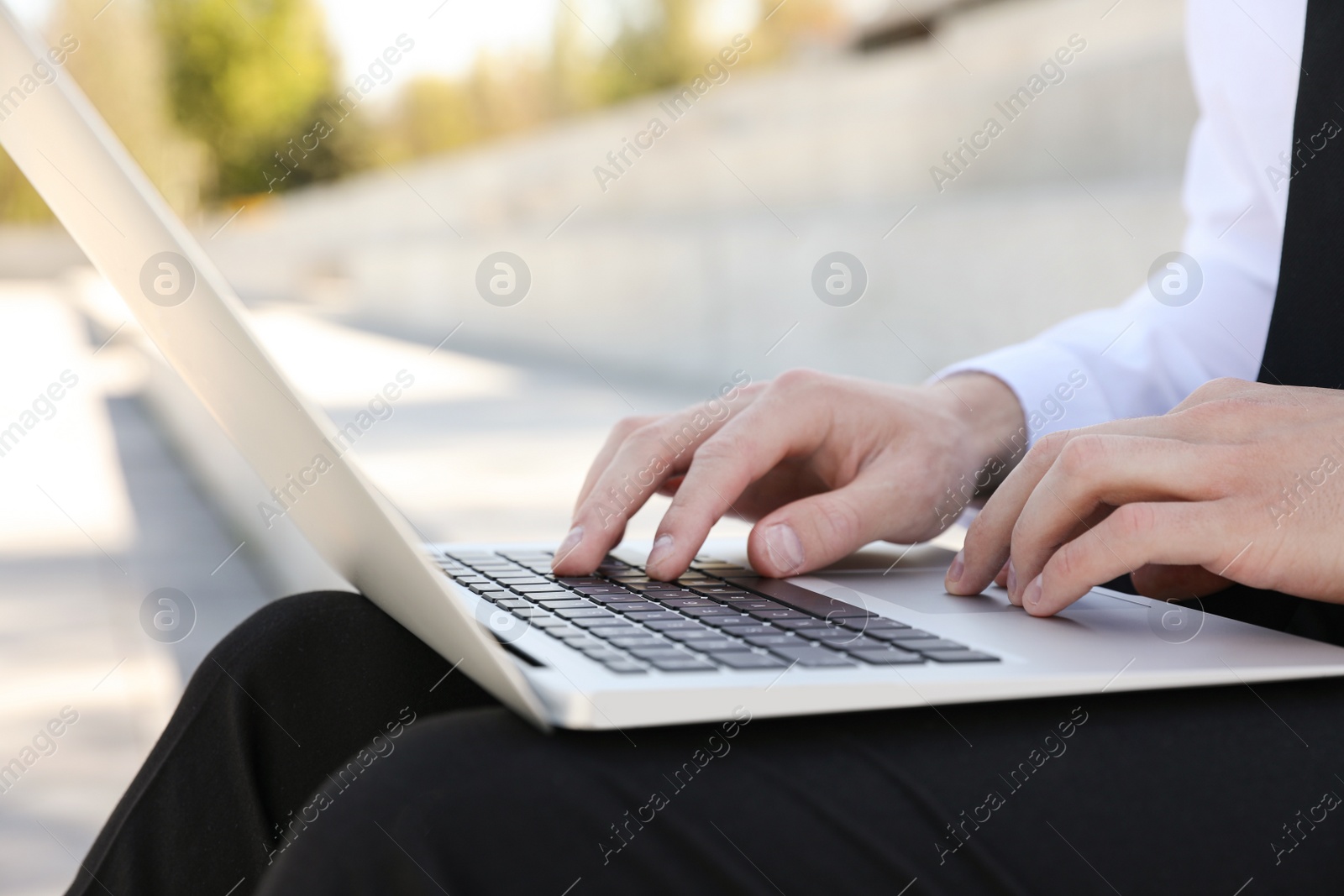 Image of Young man working on laptop outdoors, closeup