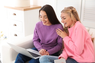Photo of Young women with laptop laughing at home