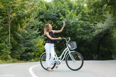 Photo of Beautiful woman in casual outfit with bicycle outdoors