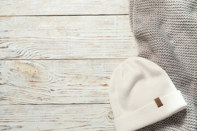 Photo of Gray knitted scarf and hat on wooden table, flat lay. Space for text